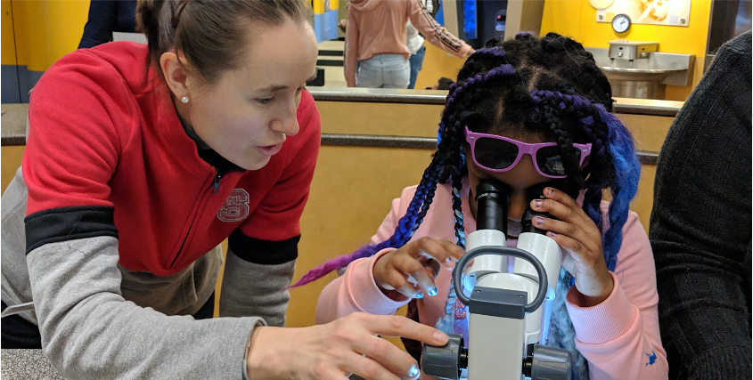 Maude Cuchiara assists a child with microscopy at the Museum of Life and Science